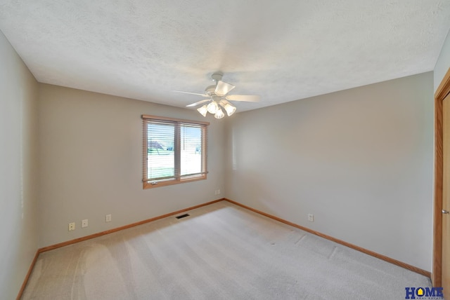 spare room featuring a textured ceiling, a ceiling fan, visible vents, light carpet, and baseboards