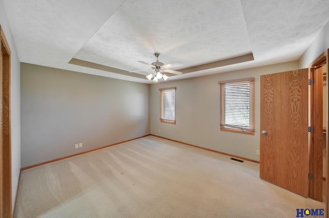 unfurnished bedroom featuring visible vents, baseboards, a textured ceiling, and a raised ceiling