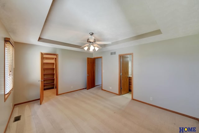 unfurnished bedroom featuring visible vents, baseboards, and a tray ceiling