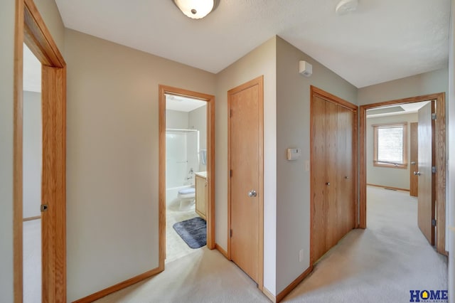 corridor featuring baseboards and light carpet