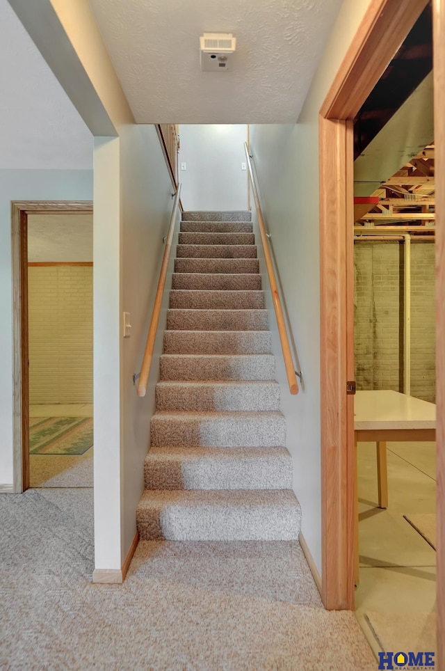 stairs featuring carpet flooring, baseboards, and a textured ceiling