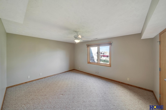 unfurnished room featuring a textured ceiling, light colored carpet, baseboards, and ceiling fan