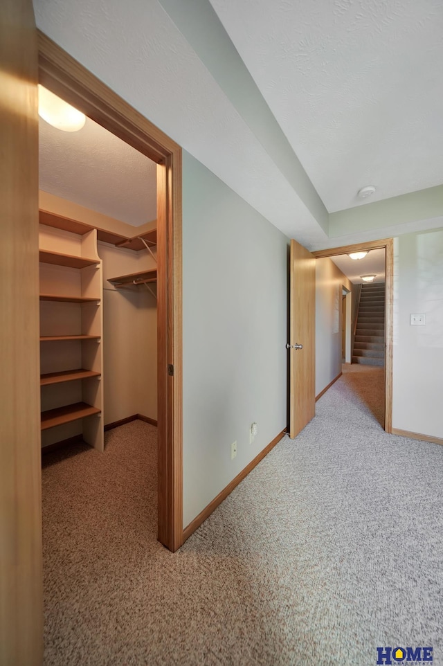 corridor featuring carpet floors, baseboards, and stairway