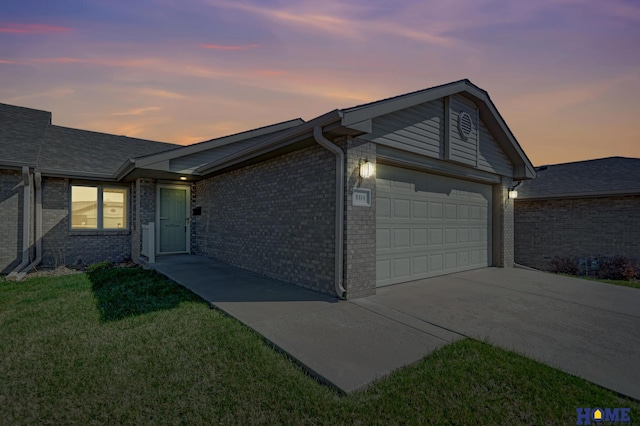 ranch-style house featuring a garage, brick siding, driveway, and a lawn