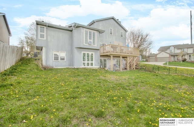 rear view of house with a lawn, a deck, and a fenced backyard