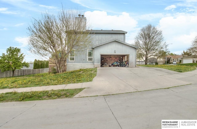view of front facade with driveway, fence, a chimney, and a garage