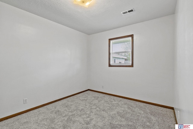 unfurnished room with baseboards, carpet flooring, a textured ceiling, and visible vents