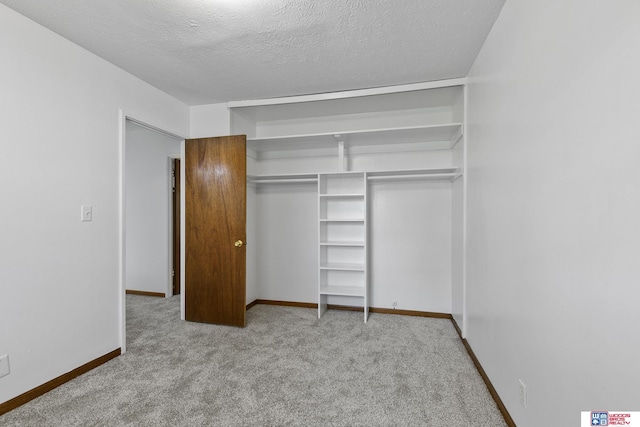 unfurnished bedroom featuring carpet floors, a textured ceiling, baseboards, and a closet
