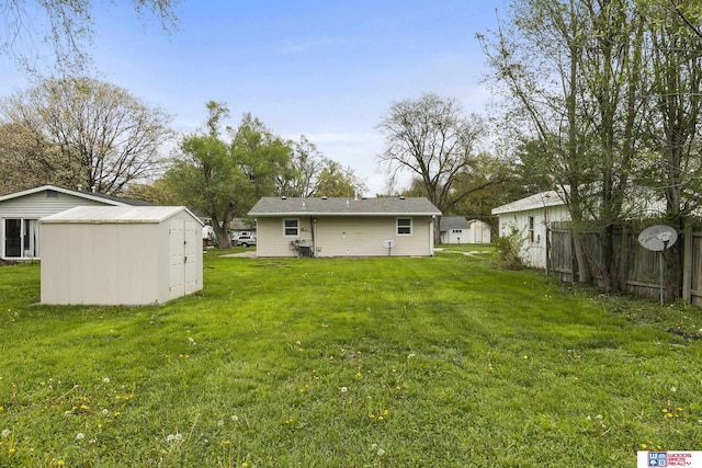 view of yard with fence, a storage unit, and an outbuilding