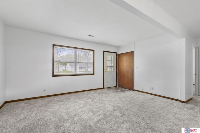 empty room with carpet floors, baseboards, and visible vents