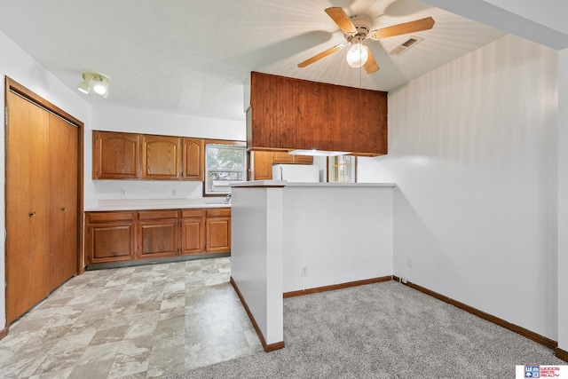 kitchen with visible vents, fridge, baseboards, brown cabinets, and a ceiling fan