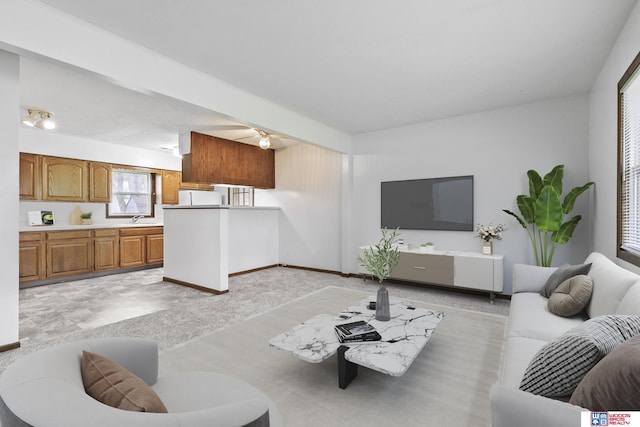 living area with baseboards, ceiling fan, and light colored carpet