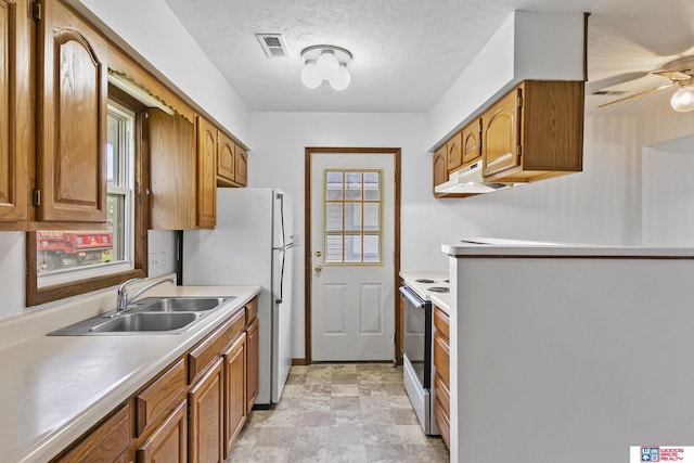 kitchen with white appliances, brown cabinetry, and a sink