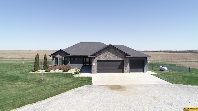 view of front of home featuring concrete driveway, stone siding, an attached garage, a front yard, and fence