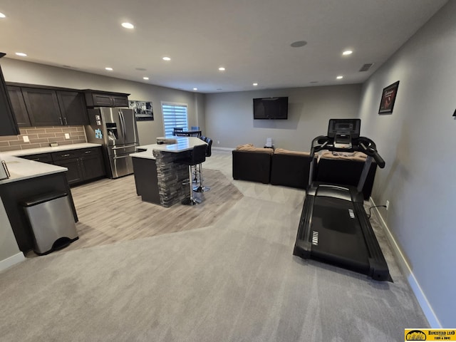 kitchen featuring tasteful backsplash, stainless steel fridge, light countertops, visible vents, and a breakfast bar area