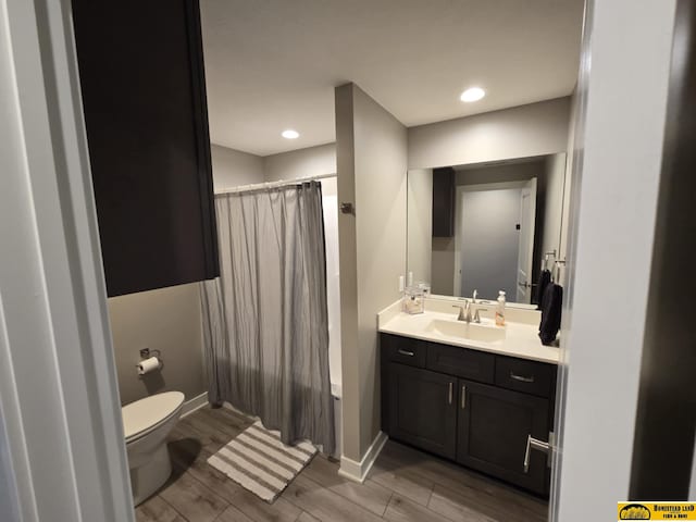 full bath with toilet, vanity, baseboards, and wood finish floors
