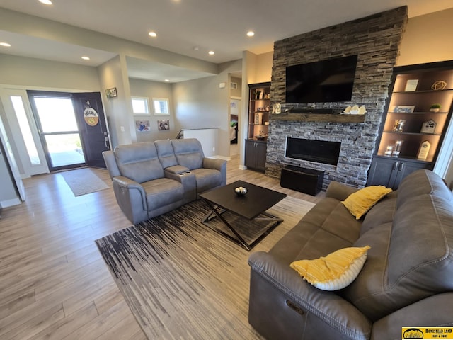 living area featuring a fireplace, light wood-style flooring, recessed lighting, baseboards, and built in shelves