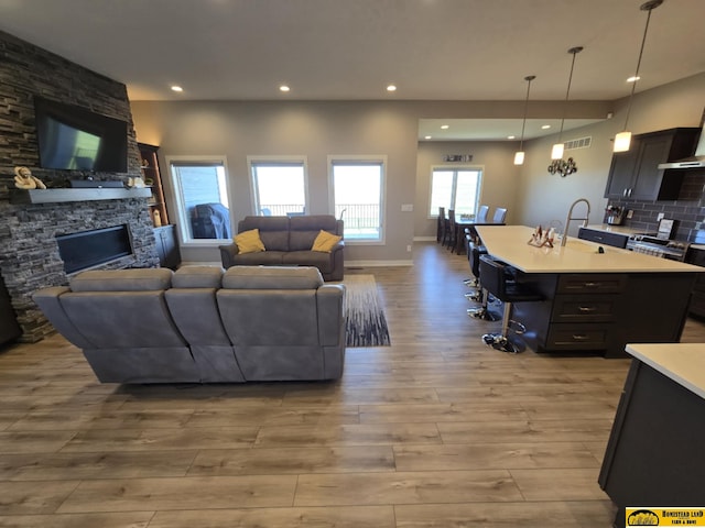 living room with visible vents, baseboards, a fireplace, light wood finished floors, and recessed lighting