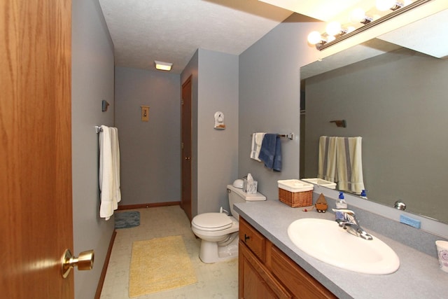 bathroom with toilet, vanity, and baseboards