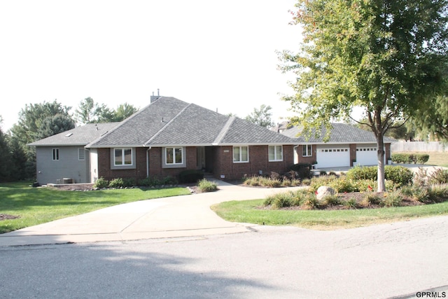 single story home featuring brick siding, a front lawn, driveway, and roof with shingles