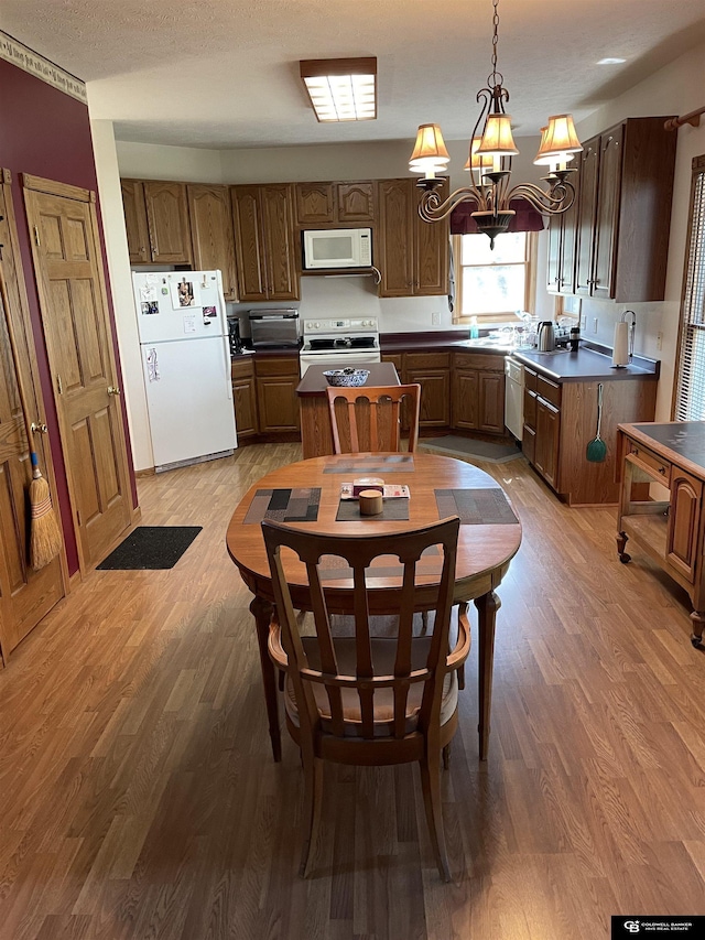 kitchen with wood finished floors, a notable chandelier, and white appliances