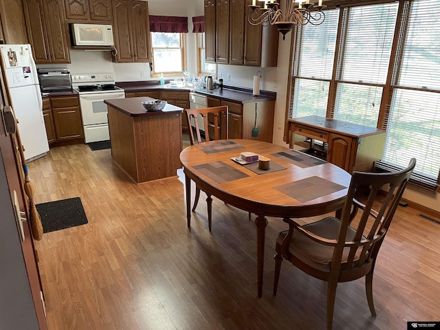 dining room with light wood-style floors, visible vents, and an inviting chandelier