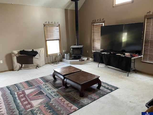 living room featuring vaulted ceiling, carpet floors, and a wood stove
