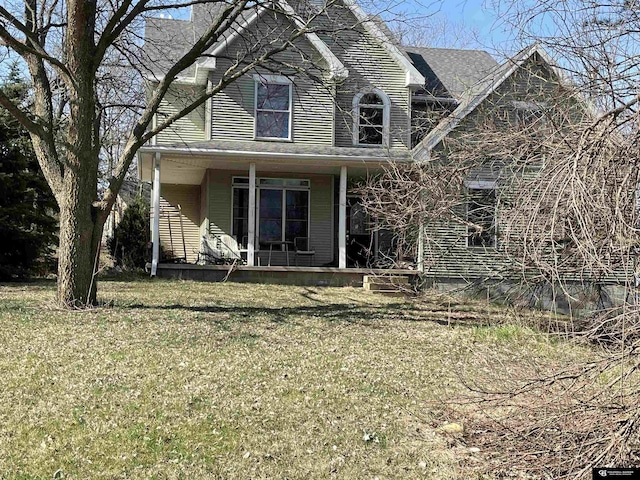rear view of property featuring a porch and a lawn