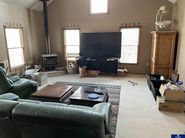 living room featuring a wood stove, lofted ceiling, and carpet floors