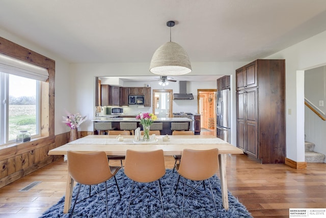 dining room featuring stairs, visible vents, light wood-type flooring, and a wainscoted wall