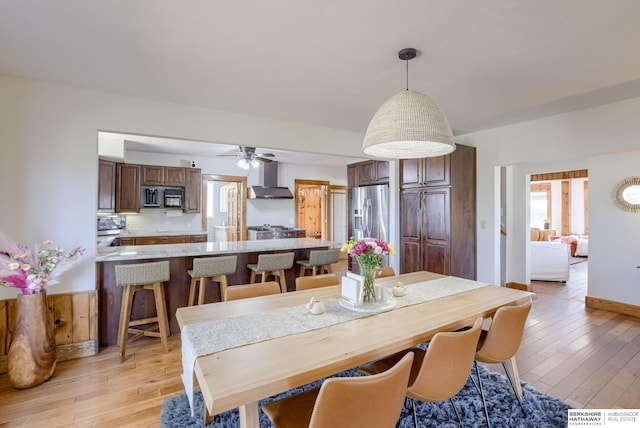 dining room featuring light wood-style flooring, ceiling fan, and baseboards