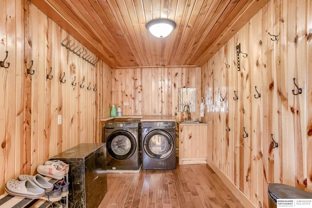 washroom featuring wood walls, laundry area, washer and dryer, wood ceiling, and a sink