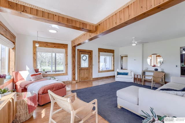 living room with beam ceiling, a wealth of natural light, light wood-type flooring, and baseboards