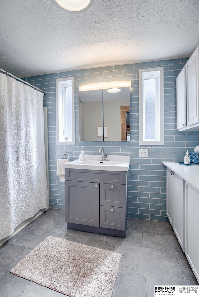 bathroom with a textured ceiling, a healthy amount of sunlight, and vanity