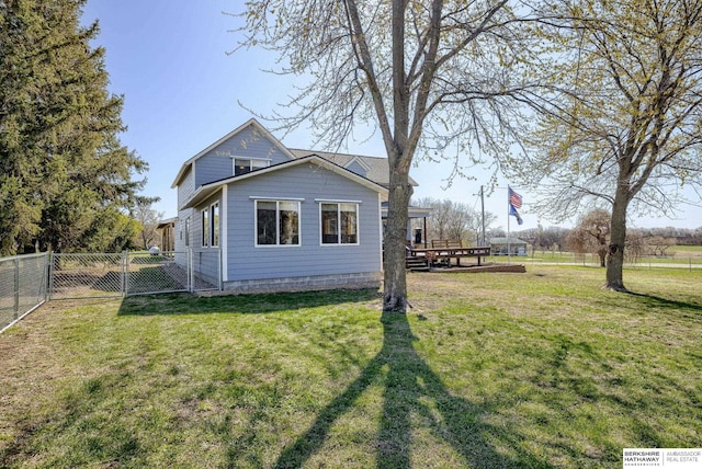 exterior space with a yard, a deck, a fenced backyard, and a gate
