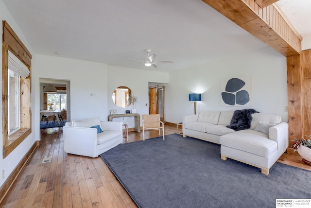 living area with baseboards, visible vents, hardwood / wood-style flooring, and a ceiling fan