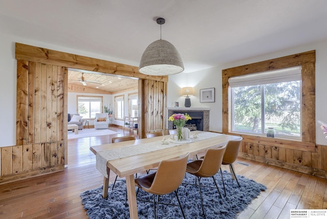 dining area with a fireplace, visible vents, vaulted ceiling, and hardwood / wood-style floors