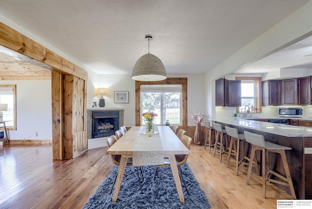 dining space with baseboards, light wood-type flooring, and a fireplace
