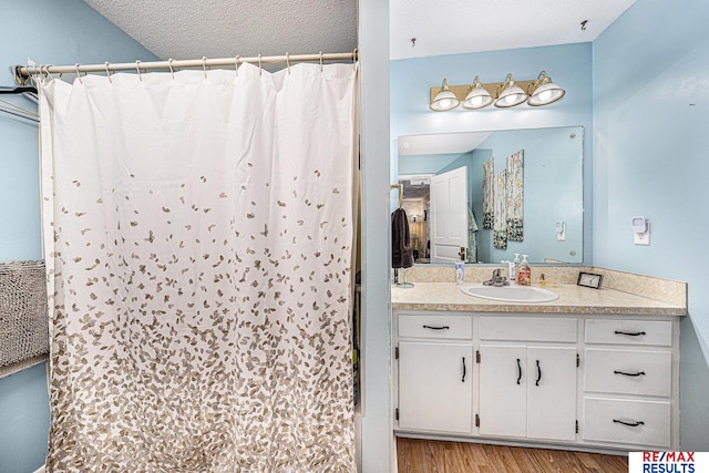 2860 335th St, Logan, IA 51546 - bathroom featuring a textured ceiling, wood finished floors, vanity, and curtained shower