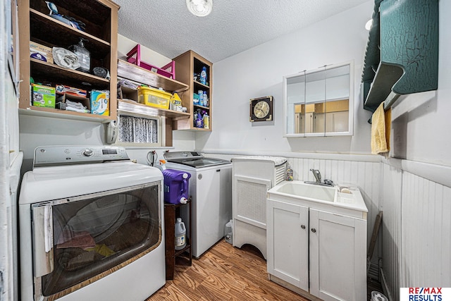 2860 335th St, Logan, IA 51546 - washroom featuring washing machine and dryer, a textured ceiling, light wood-style floors, wainscoting, and a sink