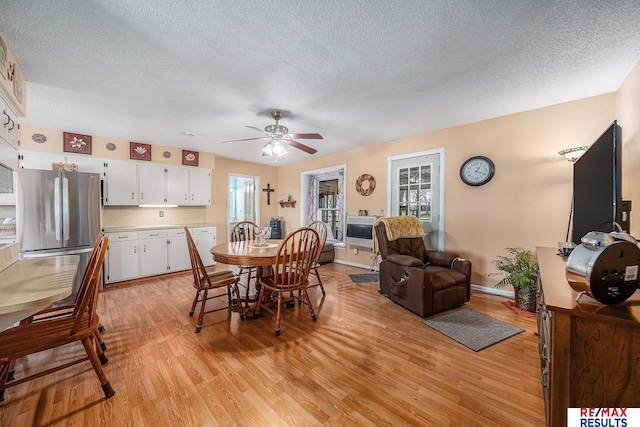 2860 335th St, Logan, IA 51546 - dining area featuring light wood-style floors, a textured ceiling, baseboards, and ceiling fan