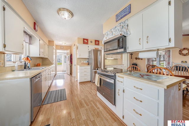 2860 335th St, Logan, IA 51546 - kitchen with light countertops, appliances with stainless steel finishes, a textured ceiling, white cabinetry, and light wood finished floors