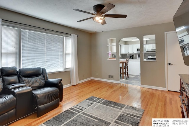 161 S Linden St, Wahoo, NE 68066 - living room featuring ceiling fan, arched walkways, light wood finished floors, and baseboards