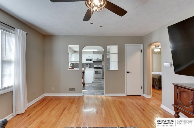 161 S Linden St, Wahoo, NE 68066 - unfurnished living room with a ceiling fan, arched walkways, light wood-type flooring, and plenty of natural light