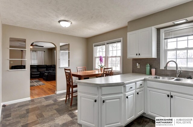 161 S Linden St, Wahoo, NE 68066 - kitchen with a sink, baseboards, arched walkways, white cabinets, and a peninsula