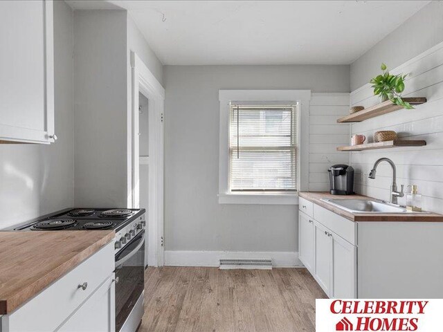 3361 N 59th St, Omaha, NE 68104 - kitchen featuring light wood-style flooring, white cabinetry, open shelves, stainless steel range with electric stovetop, and a sink