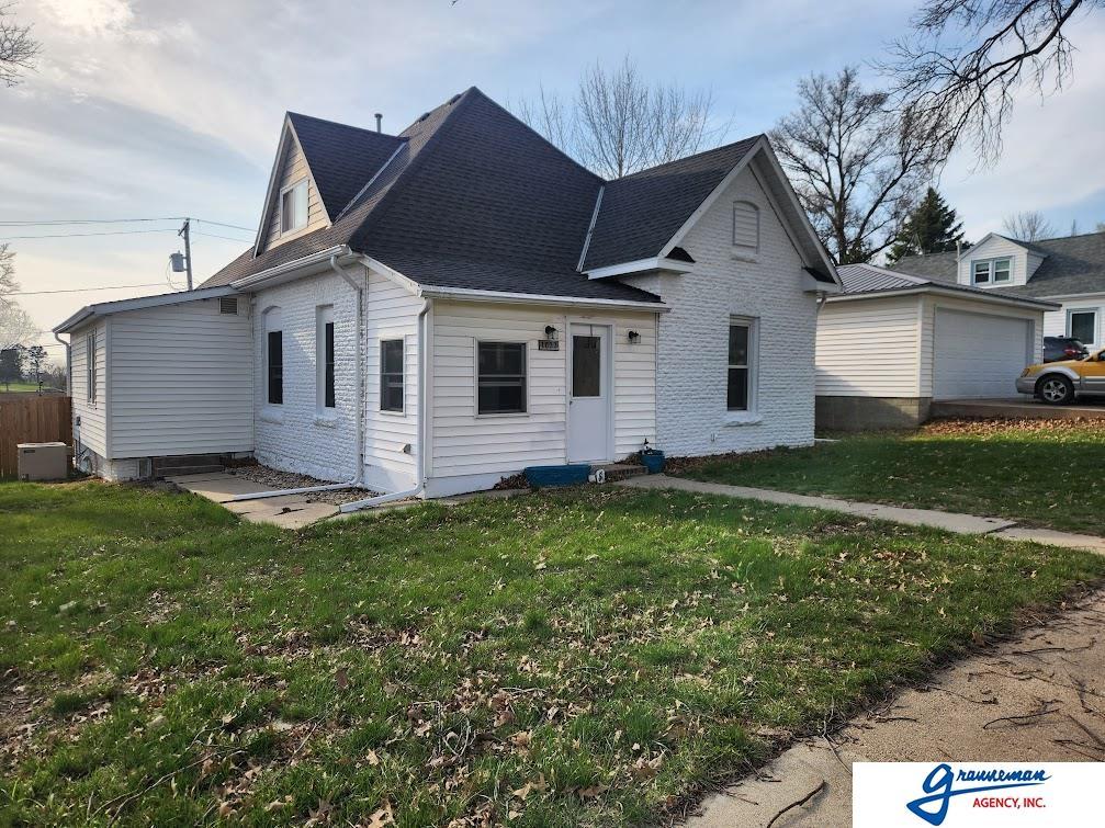 exterior space with a yard, brick siding, a garage, and roof with shingles