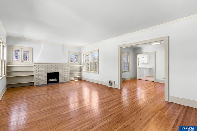 unfurnished living room with a fireplace, light wood finished floors, visible vents, and baseboards