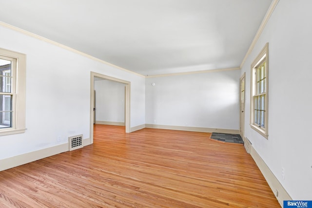 empty room with light wood finished floors, baseboards, ornamental molding, and visible vents