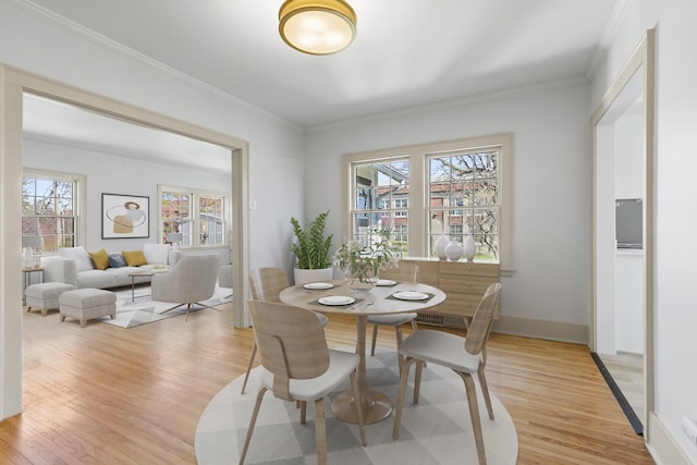 dining area featuring light wood-style floors, baseboards, and ornamental molding